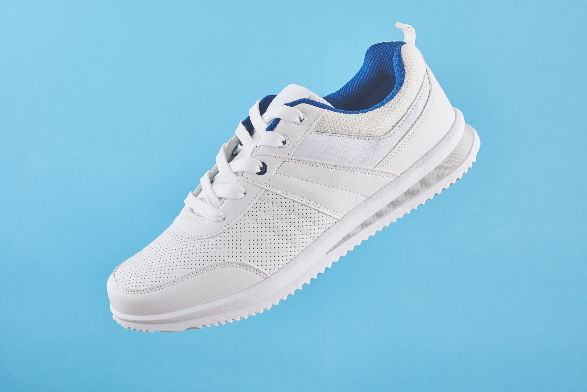 A white sneaker with a blue lining against a light blue background